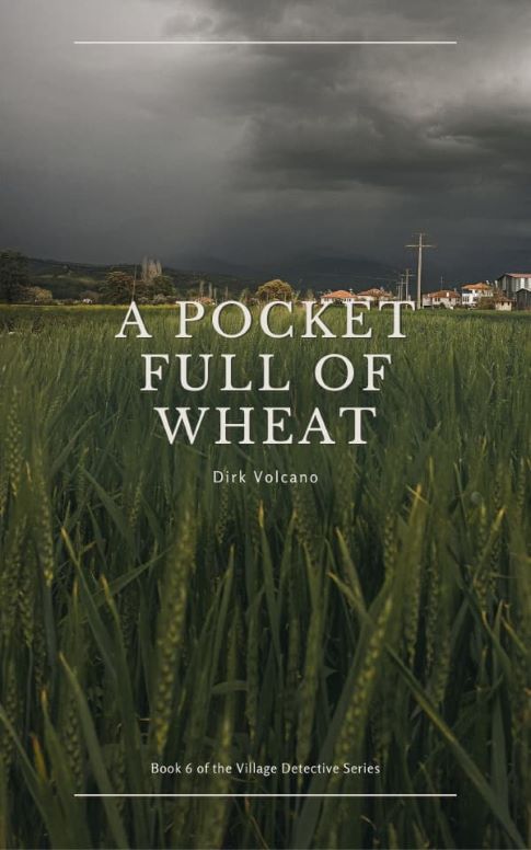 Book cover for "A Pocket Full of Wheat" by Dirk Volcano, book 6 of the Village Detective Series. Features a green wheat field in the foreground with a distant village under an overcast sky, the title in serif text at the center, and the author’s name below.